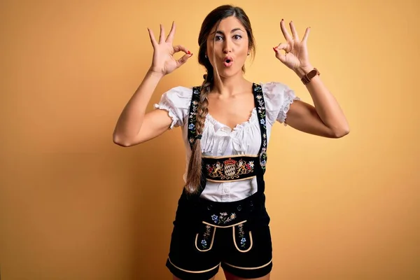 伝統的なドレスを着て10月祭を祝う若い美しいブルネットのドイツ人女性は驚きとショックを受け 指でOk承認シンボルを行う 狂気の表現 — ストック写真