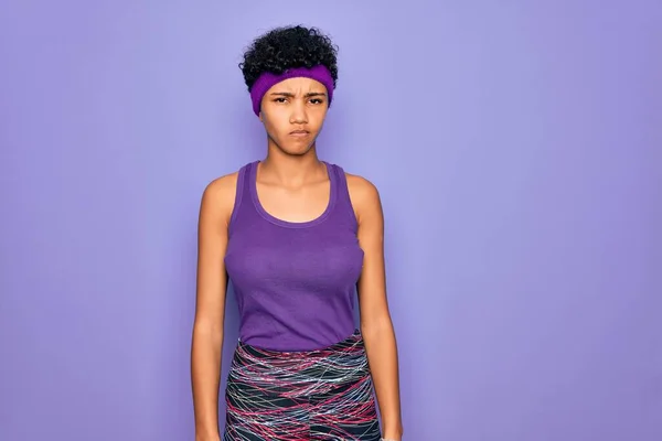 紫の背景にカジュアルなスポーツウェアを身に着けている美しいアフリカ系アメリカ人のアフロ女性は懐疑的で緊張し 問題のために動揺を眉をひそめている 負の人 — ストック写真