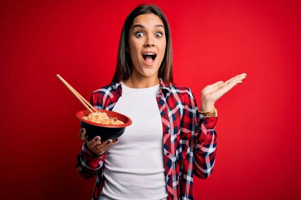Joven Hermosa Morena Comiendo Fideos Usando Palillos Sobre Fondo Rojo —  Fotos de Stock