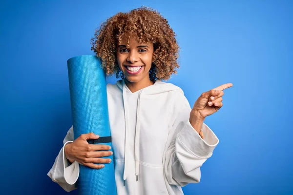 Junge Afrikanisch Amerikanische Sportlerin Hält Yogamatte Über Isoliertem Blauem Hintergrund — Stockfoto