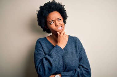 Kıvırcık saçlı, sıradan bir kazak giyen genç ve güzel Afro-Amerikan kadın bir soru hakkında endişeli ve gergin bir şekilde düşünüyor.