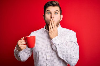 Sarışın, sakallı ve mavi gözlü genç bir işadamı kırmızı fincan kahve içiyor. Ağzı kapalı. Yanlışlıkla şok olmuş, korku ifadesi, sessizlikten korkmak, gizli bir kavram.