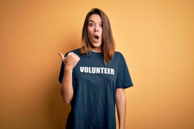 Genç, güzel, esmer bir kız gönüllü olarak tişört giyip gönüllü olarak mesaj yolluyor. El ile işaret ediyor, ağzı açık, hayret verici bir ifade..