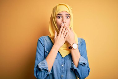 Sarı arka planda duran Müslüman başörtüsü takan genç ve güzel bir kız yanlışlıkla ağızlarını kapatarak şok geçirdi. Gizli konsept.