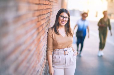 Mutlu ve kendinden emin gülümseyen genç ve güzel bir kadın. Yüzünde tebessümle kasaba sokaklarının duvarına yaslanarak duruyorum.