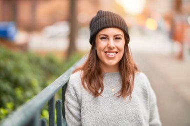 Mutlu ve kendinden emin gülümseyen genç ve güzel bir kadın. Yüzünde gülümsemeyle kentte yürürken