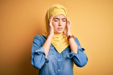 Genç, güzel bir kız, izole edilmiş sarı arka planda duruyor. Başı ağrıyor çünkü stres altında. Migren ağrısı..