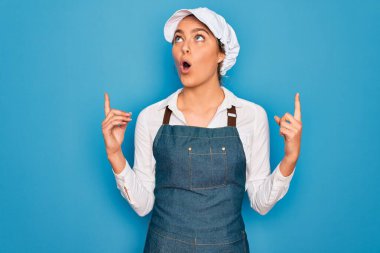 Genç, sarışın fırıncı kadın, mavi gözlü, önlük takan, şapkalı, şaşkın ve şaşkın, parmaklarıyla işaret eden ve kollarını kaldıran..