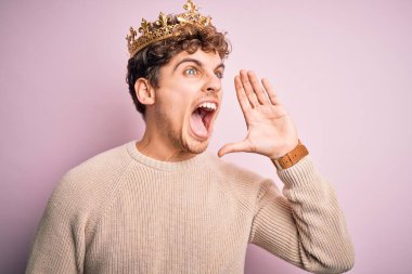 Kıvırcık saçlı, pembe arka planda kralın altın tacını takan genç sarışın adam el ele tutuşarak bağırıyor ve bağırıyordu. İletişim konsepti.