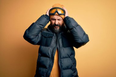 Sakallı, kar maskesi takan, kar maskesi takan ve baş ağrısı ve ağrı ve migren yüzünden stres altında olan yakışıklı, kel bir kayakçı. Ellerini başının üstüne koy..