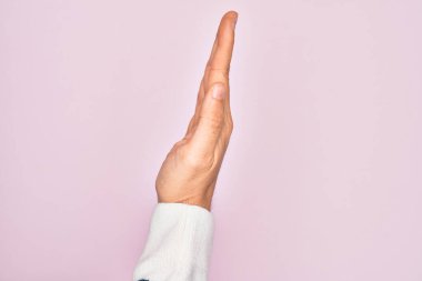 Kafkasyalı bir gencin elleri pembe arka planda parmaklarını gösteriyor. Uzanmış el hareketlerini gösteriyor.