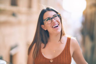 Mutlu ve kendinden emin gülümseyen genç ve güzel bir kadın. Kasaba caddesinde yüzünde gülümsemeyle dikilirken