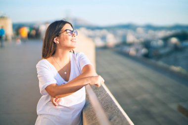 Mutlu ve kendinden emin gülümseyen genç ve güzel bir kadın. Kasaba caddesinde yüzünde gülümsemeyle dikilirken