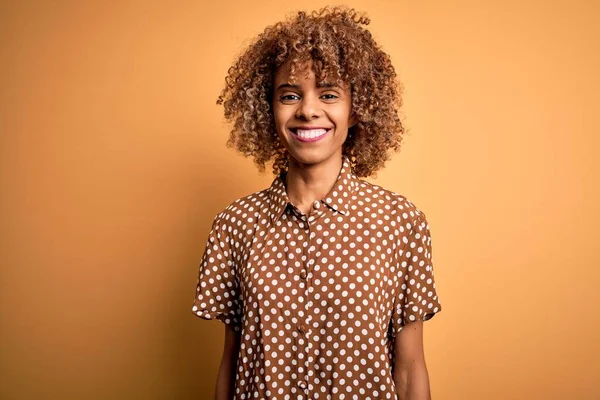 若い美しいアフリカ系アメリカ人女性は 幸せとクールな笑顔で黄色の背景に立ってカジュアルなシャツを着ています 運のいい人 — ストック写真