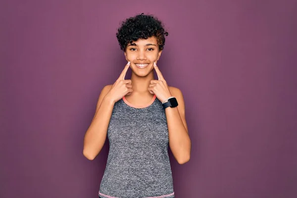 年轻美丽的非洲裔美国女运动员穿着运动服做运动 张开嘴笑着 手指指尖着 露出愉快的微笑 — 图库照片