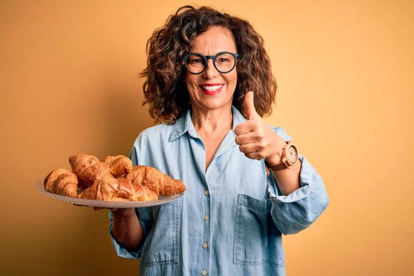 Middelbare Leeftijd Mooie Vrouw Met Bord Met Croissants Geïsoleerde Gele — Stockfoto