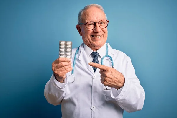 Kıdemli Gri Saçlı Doktor Elinde Ilaç Haplarıyla Mavi Arka Planda — Stok fotoğraf
