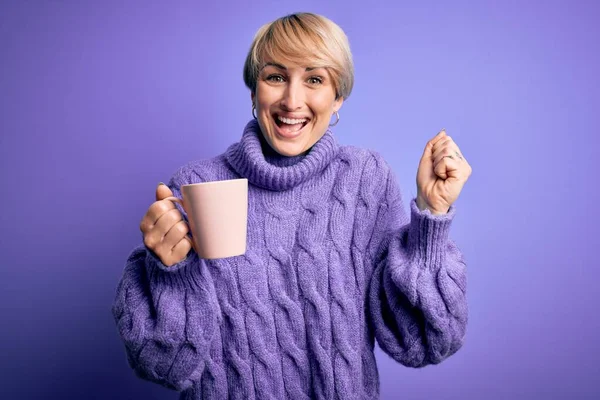 若いですブロンド女性とともに短い髪身に着けている冬のセーター飲むAカップの熱いコーヒー悲鳴誇りと勝利と成功を祝う非常に興奮 応援感情 — ストック写真