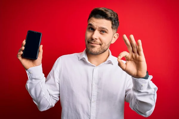 Junger Geschäftsmann Mit Blauen Augen Zeigt Smartphone Bildschirm Über Rotem — Stockfoto