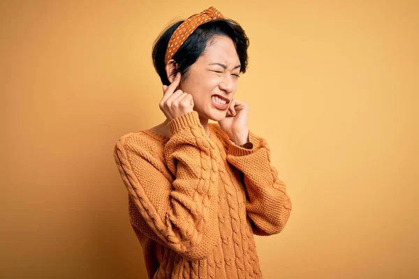 스웨터 위에서 아름다운 아시아 소녀는 시끄러운 음악을 짜증나는 표정으로 손가락으로 — 스톡 사진
