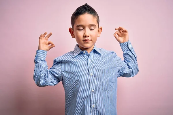 ピンクの孤立した背景の上に立つエレガントなシャツを着ている若い男の子は 指で瞑想のジェスチャーをして閉じ目でリラックスして笑顔 ヨガのコンセプト — ストック写真