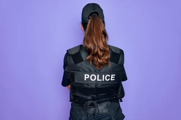 若いです警察の女性身に着けていますセキュリティ防弾ベスト制服以上紫の背景立って後方離れて見ますとともに交差腕 — ストック写真