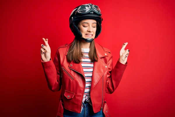 若い美しいブルネットのオートバイのヘルメットと赤いジャケットジェスチャーの指を身に着けているオートバイの女性は希望と目を閉じて笑顔を越えました 幸運と迷信の概念 — ストック写真