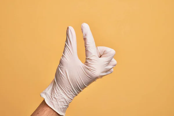 Mão Jovem Caucasiano Com Luva Médica Sobre Fundo Amarelo Isolado — Fotografia de Stock