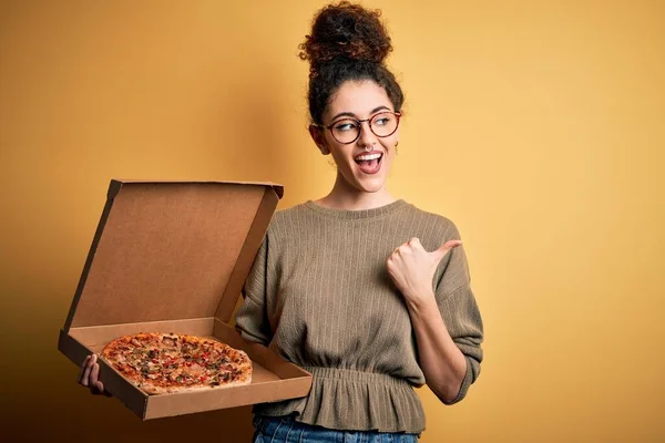 年轻美丽的女人 卷曲的头发 带着意大利比萨饼的刺眼的提箱 带着快乐的面带微笑站在旁边 — 图库照片