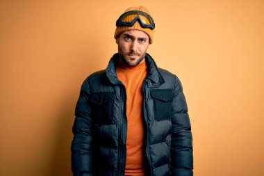 Kar giysileri ve kayak gözlüğü takan sakallı yakışıklı kayakçı şüpheci ve gergin, sorun yüzünden surat asıyor. Negatif kişi.
