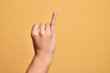 Kafkasyalı bir gencin parmağı, izole edilmiş sarı arka planda serçe parmağı, bir numaralı söz sözü olarak gösteriyor.