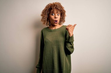 Güzel, kıvırcık saçlı, beyaz arka planda sıradan süveter giyen Afro-Amerikan bir kadın..