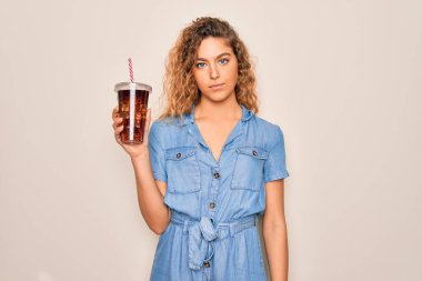 Mavi gözlü, güzel sarışın kadın kola içiyor. saman kullanarak kendine güvenen bir ifade takınıyor ve ciddi düşünüyor.