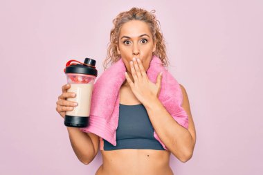Güzel sarışın spor yapan spor yapan, havluyla sallanan, ağzı ağızla kaplanmış protein içeceğiyle sarsılan, şok olan ve hata yapmaktan korkan bir kadın. Şaşırtıcı ifade.