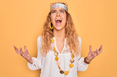 Genç, sarışın, mavi gözlü, güneş gözlüklü, aksesuar takan deli deli deli bağıran, sinirli ifadeli ve kollarını kaldırmış bir kadın. Hayal kırıklığı konsepti.