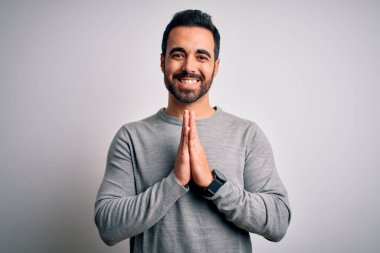 Sakallı, sıradan bir süveter giyen, elleri bağlı dua eden, kendinden emin bir şekilde gülümseyerek af dileyen genç yakışıklı bir adam..