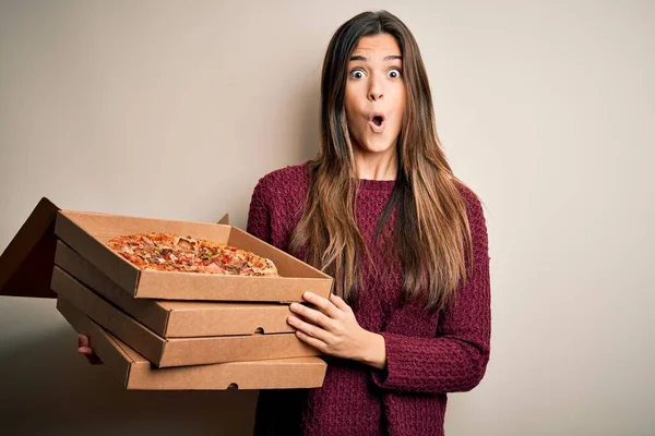 年轻而漂亮的姑娘拿着装有意大利披萨的送货箱 站在白色的背景上 吓得满脸诧异 吓得面无血色 吓得面无血色 — 图库照片