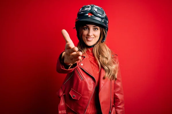 赤い背景の上に元ヘルメットを身に着けている若い美しいブルネットのオートバイの女性は 挨拶や歓迎として握手を提供する優しい笑顔 成功事業 — ストック写真