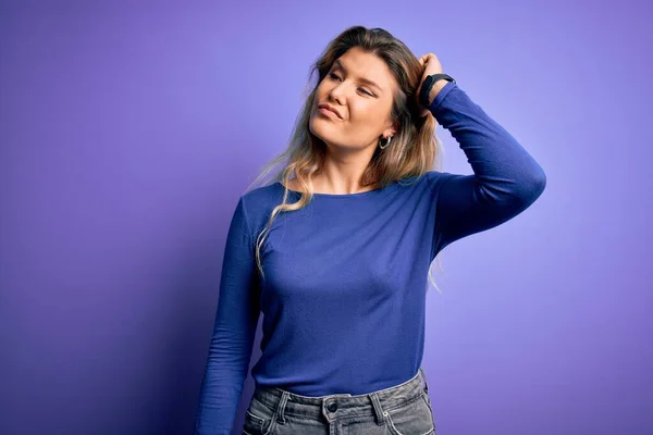 Young beautiful blonde woman wearing casual t-shirt over isolated purple background confuse and wondering about question. Uncertain with doubt, thinking with hand on head. Pensive concept.