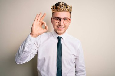 İzole edilmiş arka planda altın taç takan yakışıklı beyaz iş adamı el ve parmaklarıyla 