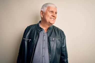 Üst düzey yakışıklı beyaz gömlekli ve ceketli adam izole edilmiş beyaz arka planda, yüzünde gülümseme, doğal bir ifade ile yan yana bakıyor. Kendinden emin gülen.