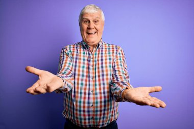 Kıdemli yakışıklı, beyaz gömlekli, soyutlanmış mor arka planda neşeli gülümsemeli, yardım eli uzatan ve kabullenen bir adam..