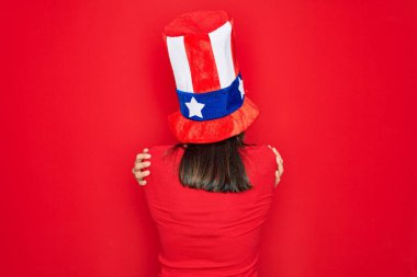 Genç, güzel esmer kadın, Amerika Birleşik Devletleri şapkası takıyor. Bağımsızlık gününü kutluyor. Kendine mutlu ve pozitif bir şekilde sarılıyor. Sevgi ve özgüven.