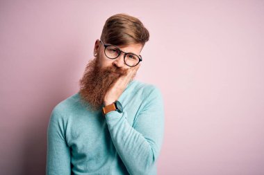 Pembe soyutlanmış arka planda gözlük takan yakışıklı kızıl saçlı yakışıklı adam çapraz kollu depresyondan sıkılmış ve yorgun görünüyor..