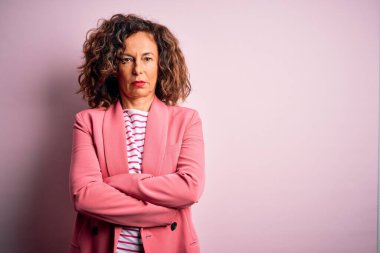 Middle age beautiful businesswoman wearing elegant jacket over isolated pink background skeptic and nervous, disapproving expression on face with crossed arms. Negative person.