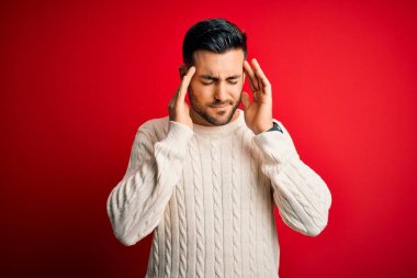 İzole edilmiş kırmızı arka plan üzerinde duran beyaz süveter giyen genç yakışıklı bir adam. Başı ağrıyan bir adam. Stres yüzünden. Migren ağrısı..