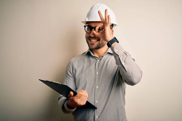 年轻的建筑师检查员头戴建筑工地安全帽 脸上挂着喜笑的剪贴板 手拿着手签 用手指看着 — 图库照片