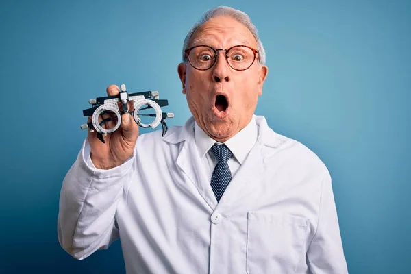 Starszy Siwowłosy Lekarz Optyk Trzymający Okulary Okulistyczne Nad Niebieskim Tłem — Zdjęcie stockowe