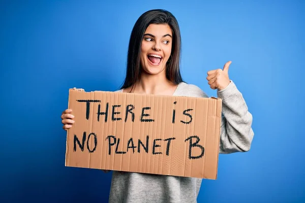 若い美しいブルネットの活動家の女性は 地球を指すと幸せな顔を笑顔で親指で側に表示するために抗議バナーを保持 — ストック写真
