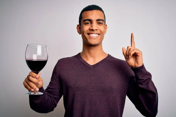 いくつかのアフリカ系アメリカ人ソムリエ男テイスティングガラスの赤ワインの白の背景に驚きでアイデアや質問を指差す指で幸せな顔 ナンバーワン — ストック写真
